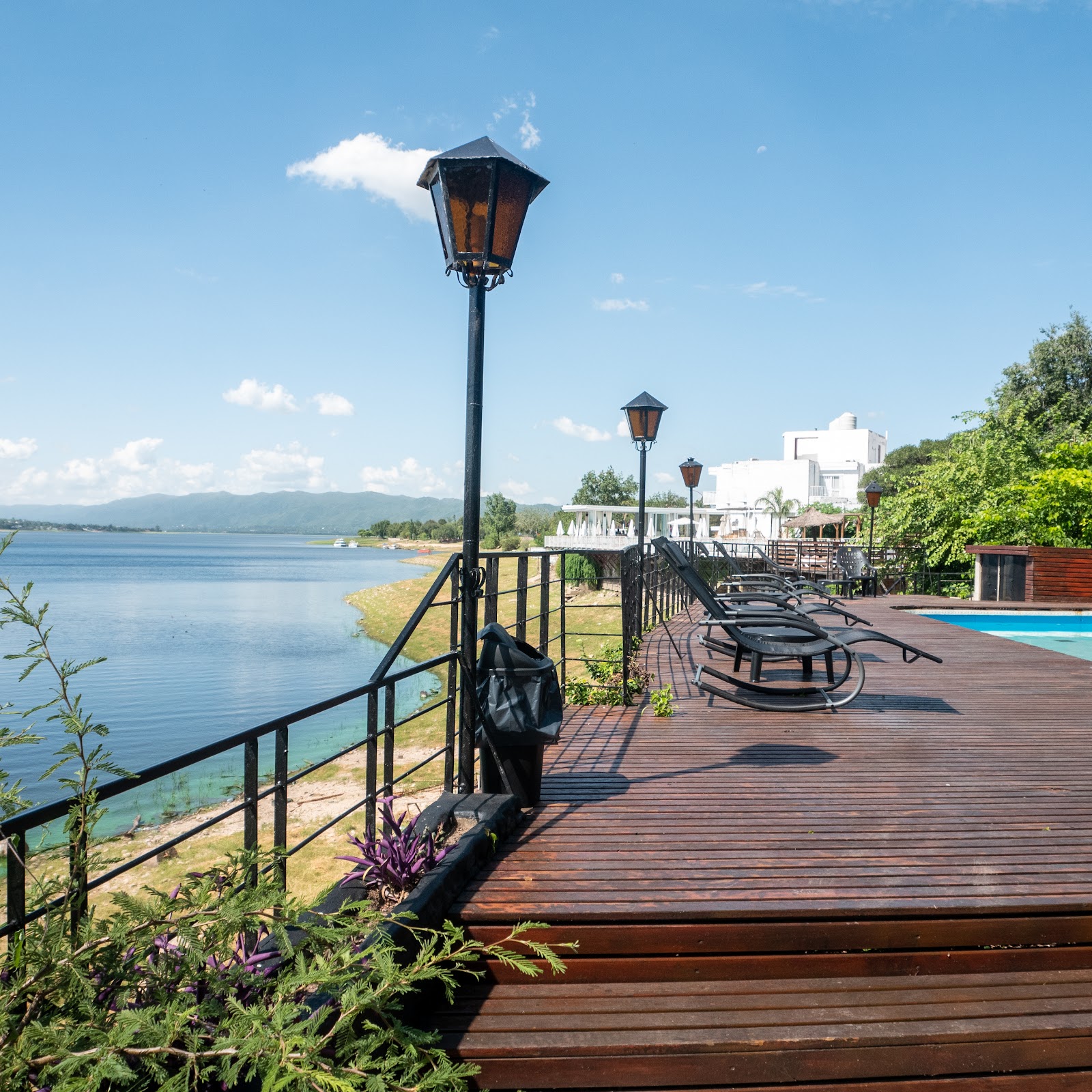 Deck de madera con reposeras y pileta frente al lago San Roque en Villa Carlos Paz